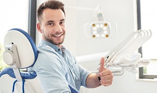 smiling man giving a thumbs up in the dental chair 