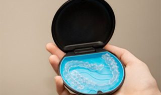 Patient holding Invisalign in black and blue storage case