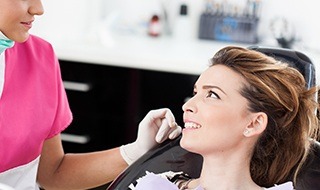 Woman in dental chair talking to dentist