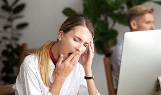 Woman at work who needs sleep apnea treatment in Burlington