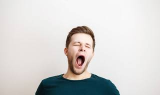 Man in blue shirt with short hair yawning