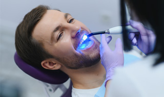 Man having UV light applied to bonding on teeth