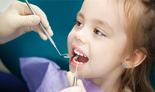 little girl with butterfly earrings getting dental checkup