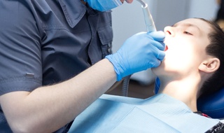 Preteen boy receiving dental sealants from male dentist