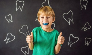 young boy wearing mouthguard and giving thumbs up