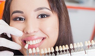 Woman's smile compared with tooth color chart