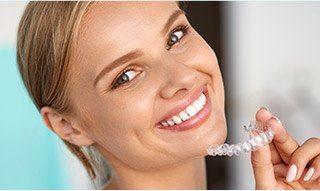 Woman holding Invisalign tray