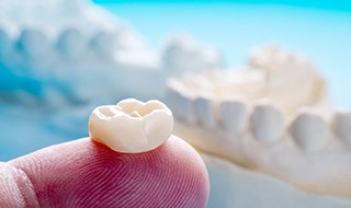 A closeup of a dental crown placed on a person’s finger