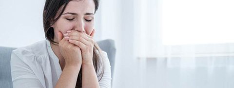 Woman with a toothache in Burlington covering her mouth