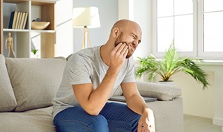 a man holding his cheek due to tooth pain