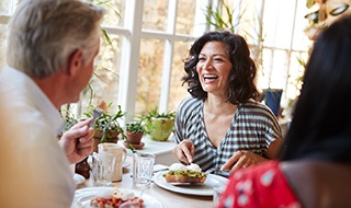 Friends smiling while eating meal in restaurant