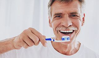 man brushing teeth after getting dental implants in Burlington