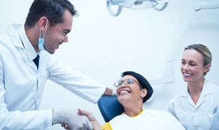 A dentist and dental assistant meet with a patient to discuss how dental implants work during a consultation in Burlington