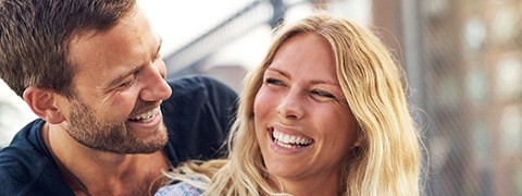 Man and woman laughing together with dental implants in Burlington