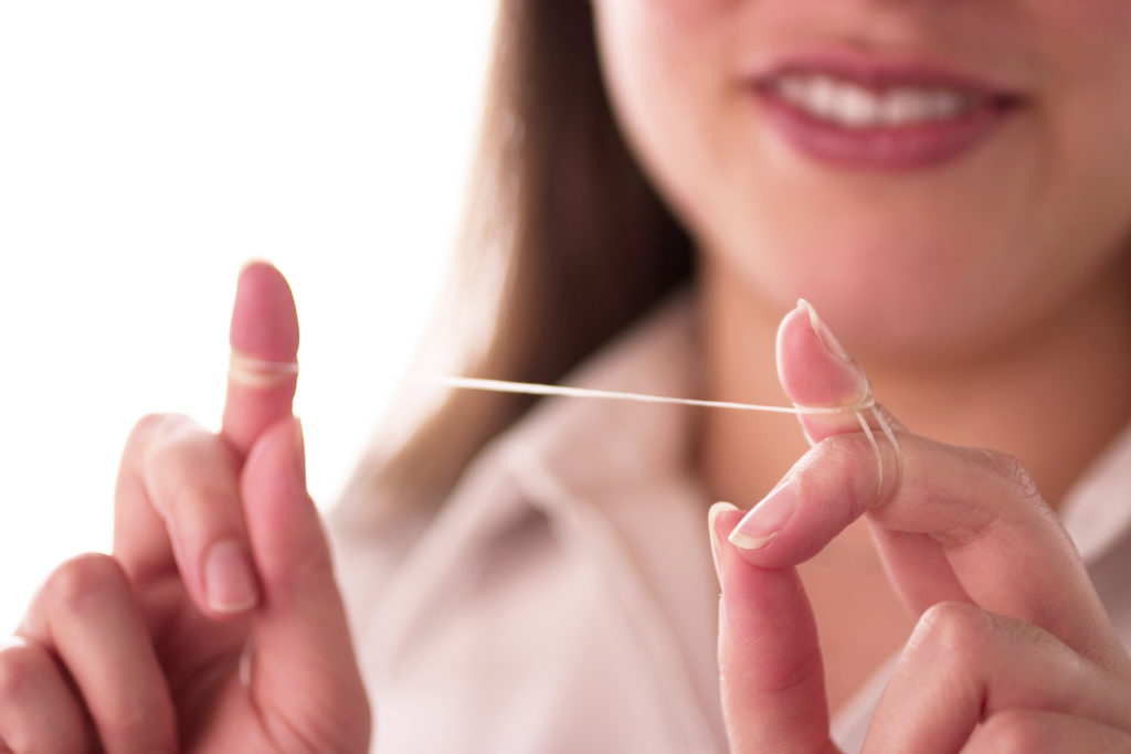 Woman flossing her teeth. 