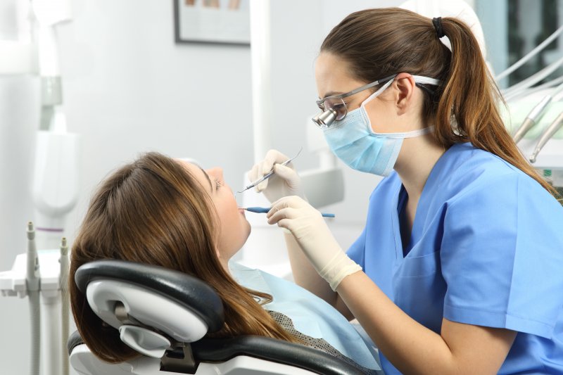 a woman having her teeth checked by a dental hygienist