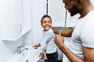 parent brushing their teeth with their child