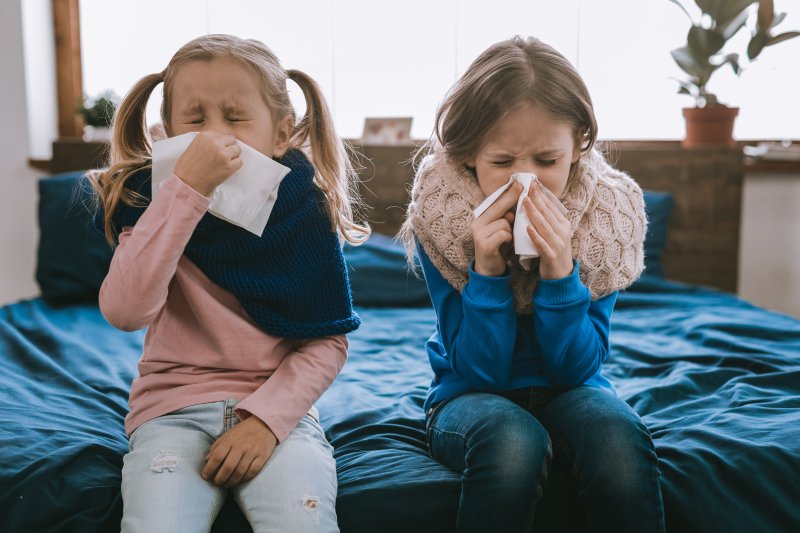 Two children blowing their nose