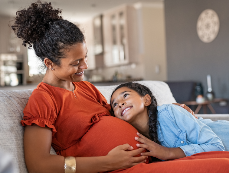 Pregnant mom with her older daughter resting on couch