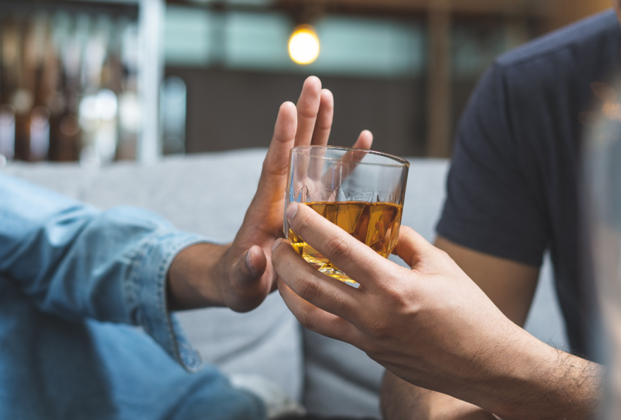 Hand pushing glass of alcohol away